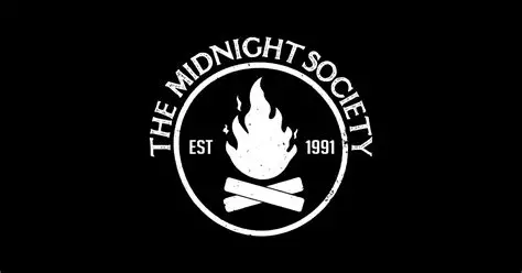 White Midnight Society emblem with a campfire, crossed logs and the words EST 1991 on a black background.