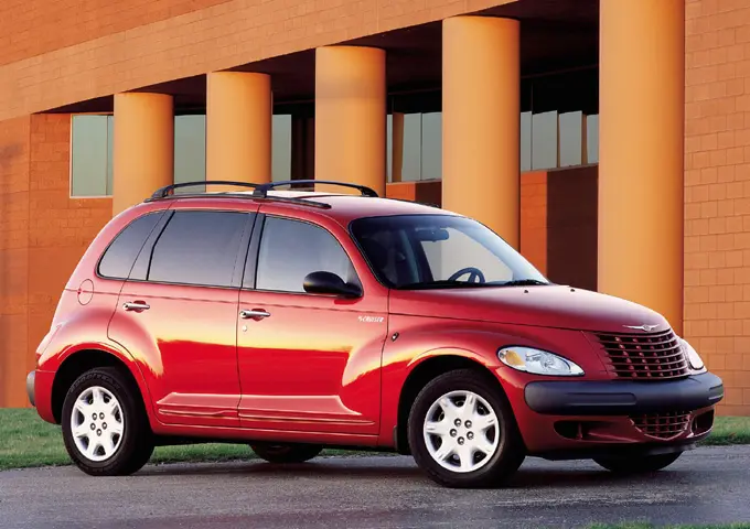 Red Chrysler PT Cruiser parked in front of an orange building with large round columns.