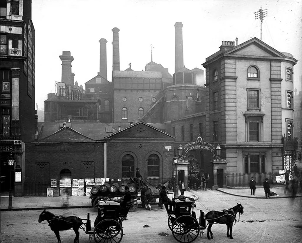 Historic black-and-white view of the Horseshoe Brewery with horse-drawn carts and beer barrels outside.