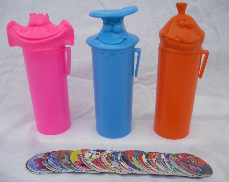 Three brightly coloured Tazo storage tubes with character-shaped lids and a fan of discs in front.