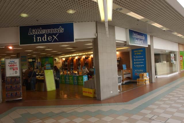 Open Littlewoods Index shop inside a shopping centre, with blue Index signs above two entrances, display stands and shoppers visible inside.