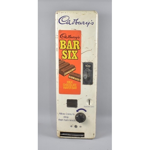 Front view of a worn white Cadbury’s vending machine with an orange panel reading ‘Cadbury’s Bar Six’ and ‘Milk Chocolate Wafer Bar’, a 10p coin slot, turning handle, and delivery slot.