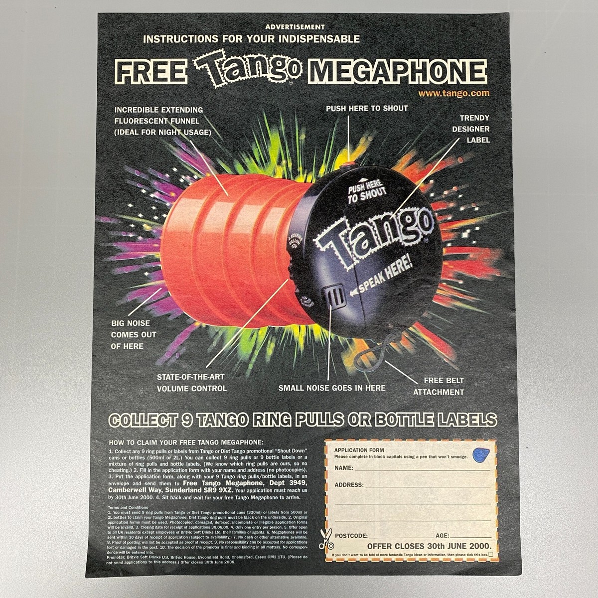 Photograph of a printed Tango Megaphone advertisement showing a large orange-and-black megaphone with labelled features, offer instructions, and an application form.