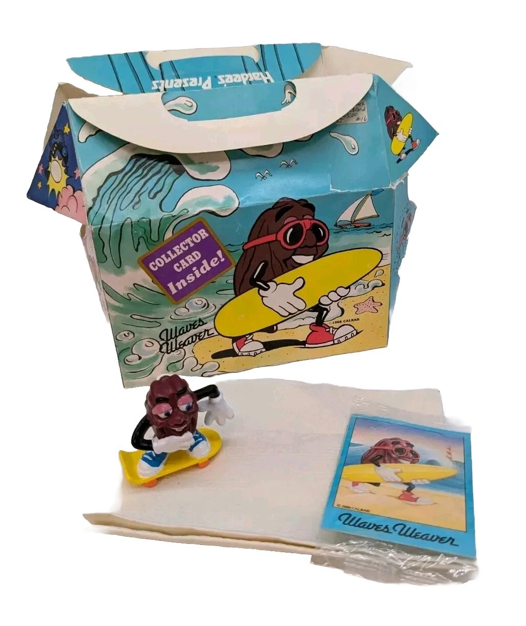 A worn blue California Raisins box with a cartoon raisin carrying a yellow surfboard is displayed with a small raisin figurine on a yellow skateboard and a matching collector card labeled "Waves Weaver."