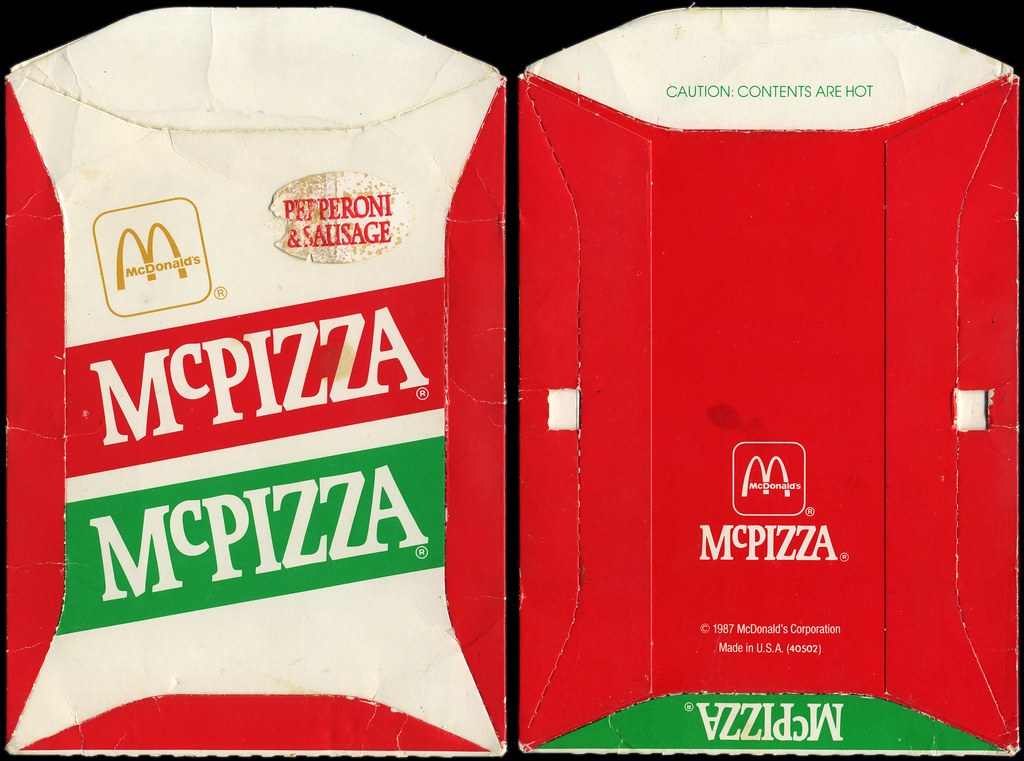 Flattened red, white, and green McPizza carton shown front and back against a black background. The front reads “Pepperoni & Sausage” and “McPizza”; the reverse includes “CAUTION: CONTENTS ARE HOT” and “© 1987 McDonald’s Corporation.”