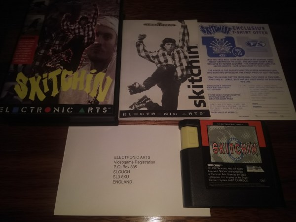 Dim overhead photograph of Skitchin' materials on a wooden table: a black game case, a printed leaflet with a skater image and "Skitchin'" text, an Electronic Arts registration card, and a black cartridge with a Skitchin' label.