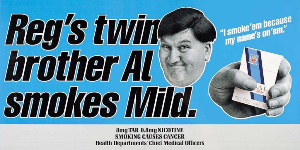 Light-blue Regal Mild cigarette advert reading “Reg’s twin brother Al smokes Mild.” A black-and-white cut-out portrait of a dark-haired man appears beside the line “I smoke ’em because my name’s on ’em.” and a hand holding a Regal Mild pack. Tar, nicotine and smoking warning text runs along the bottom.