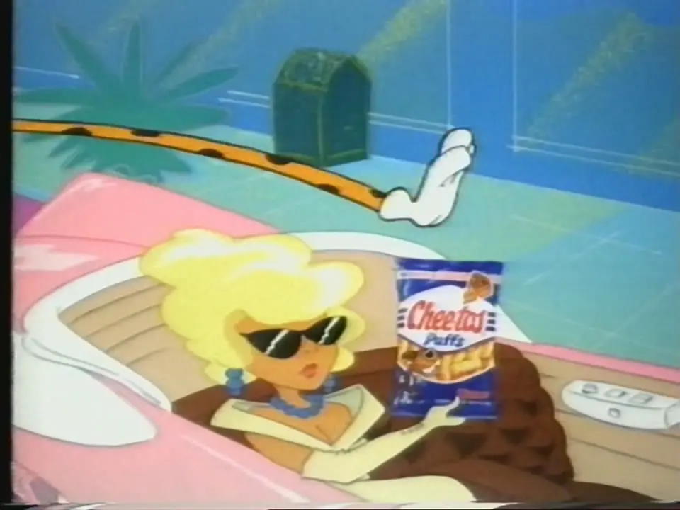 Low-resolution animated frame showing a blonde woman in black sunglasses seated in a pink convertible, holding a blue-and-white bag labelled “Cheetos Puffs”; a long orange, black-spotted arm with a white-gloved hand extends above the car.