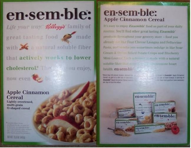 Color photograph of the front and back of a green-bordered en·sem·ble Apple Cinnamon Cereal box. The front shows a bowl of ring-shaped cereal with apple slices and cinnamon sticks; the back contains product text and a small illustration of other en·sem·ble packages.