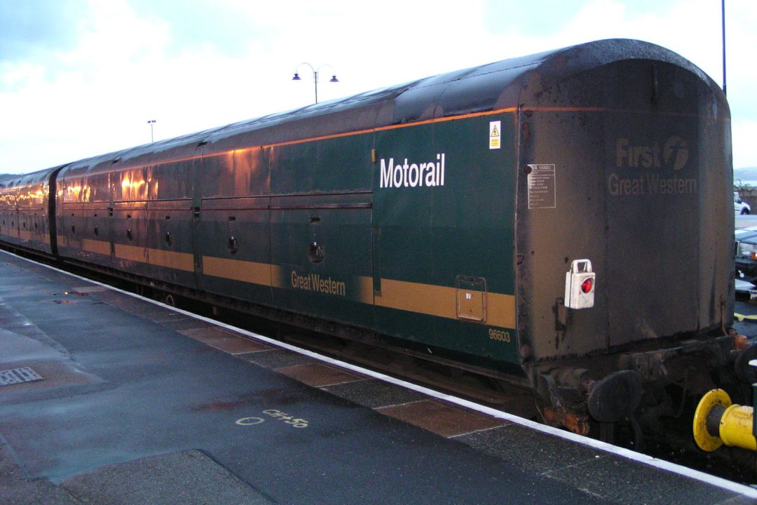 A green First Great Western railway van with Motorail lettering stands beside a station platform.