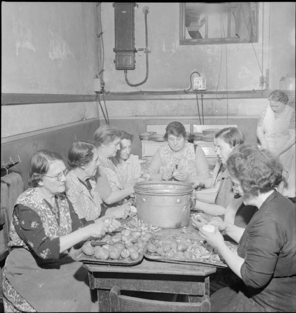 Kitchen staff prepare vegetables around a table at Woolmore Street British Restaurant in 1942.