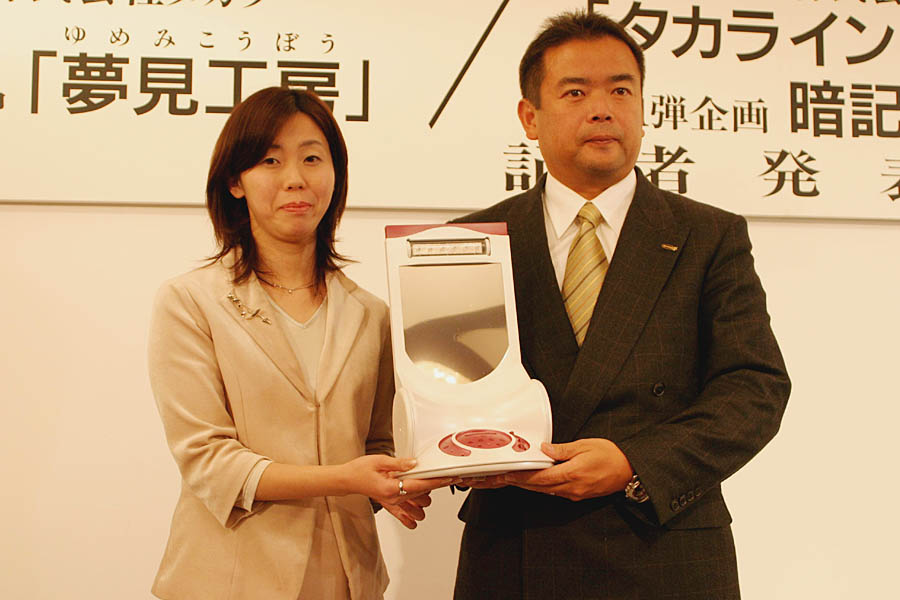 Presenters display Takara's Yumemi Kobo at its January 2004 announcement in Japan, introducing a consumer device marketed around the possibility of influencing dreams.