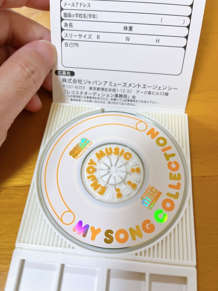 An opened RECOSTA recording case showing its branded disc and printed information card, documenting the physical souvenir customers could take home.