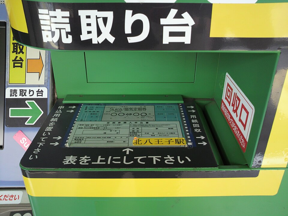 Document-reading table holding a railway application form beneath Japanese placement instructions.