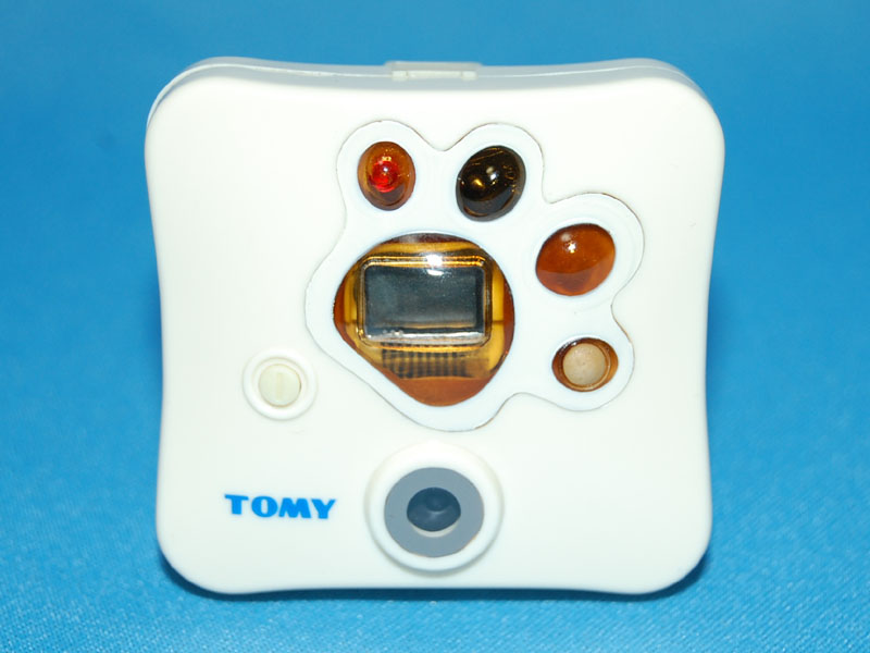 Front view of Tomy's Wonderful Shot camera, showing its white casing, paw-print control layout and TOMY branding.