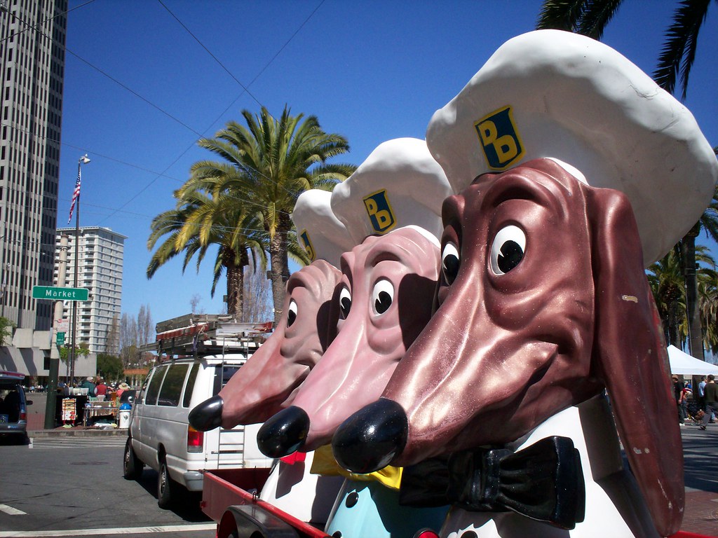 Three Doggie Diner mascot-head variants displayed together on a street trailer.