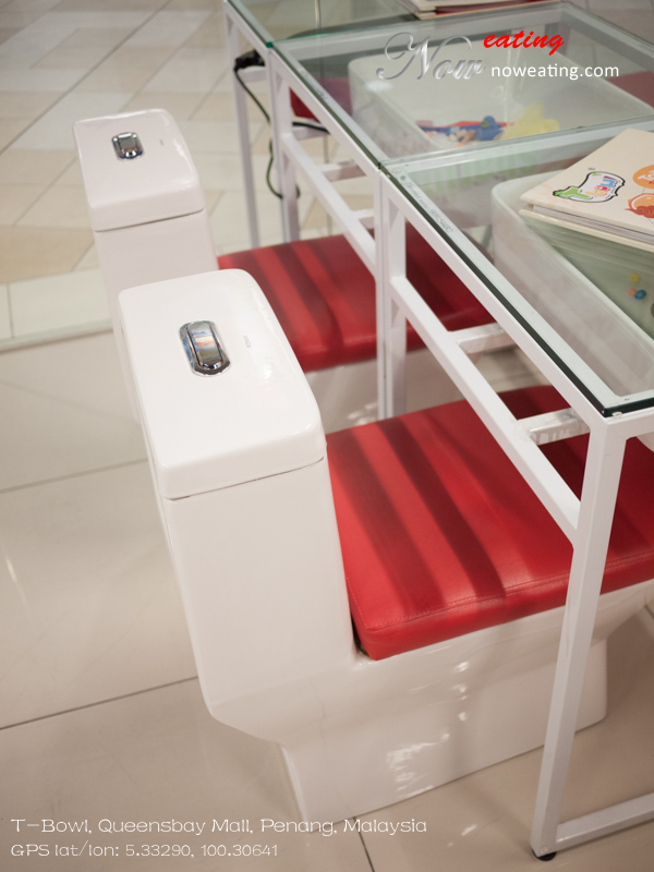 White ceramic toilet seats with red cushions beside a glass-topped dining table.