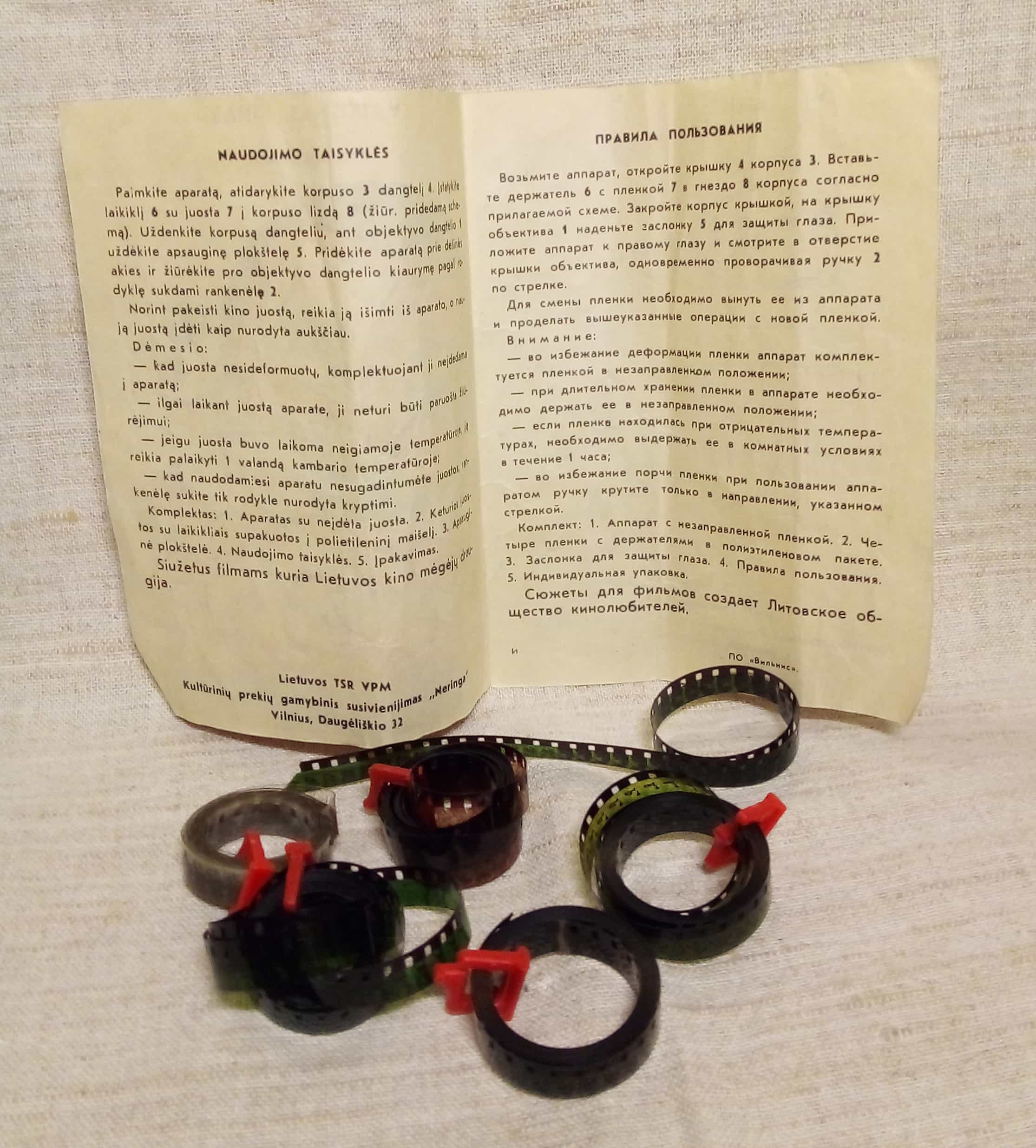 The bilingual Lithuanian and Russian instructions explain the ritual: load a loop, hold the eyepiece to the light and turn the crank to bring the tiny film to life.