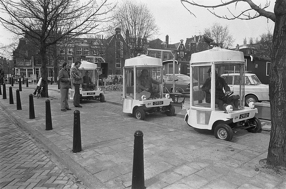 At the Amstelveld station, waiting Witkars turned the tiny vehicle into a shared network rather than a one-off electric prototype.