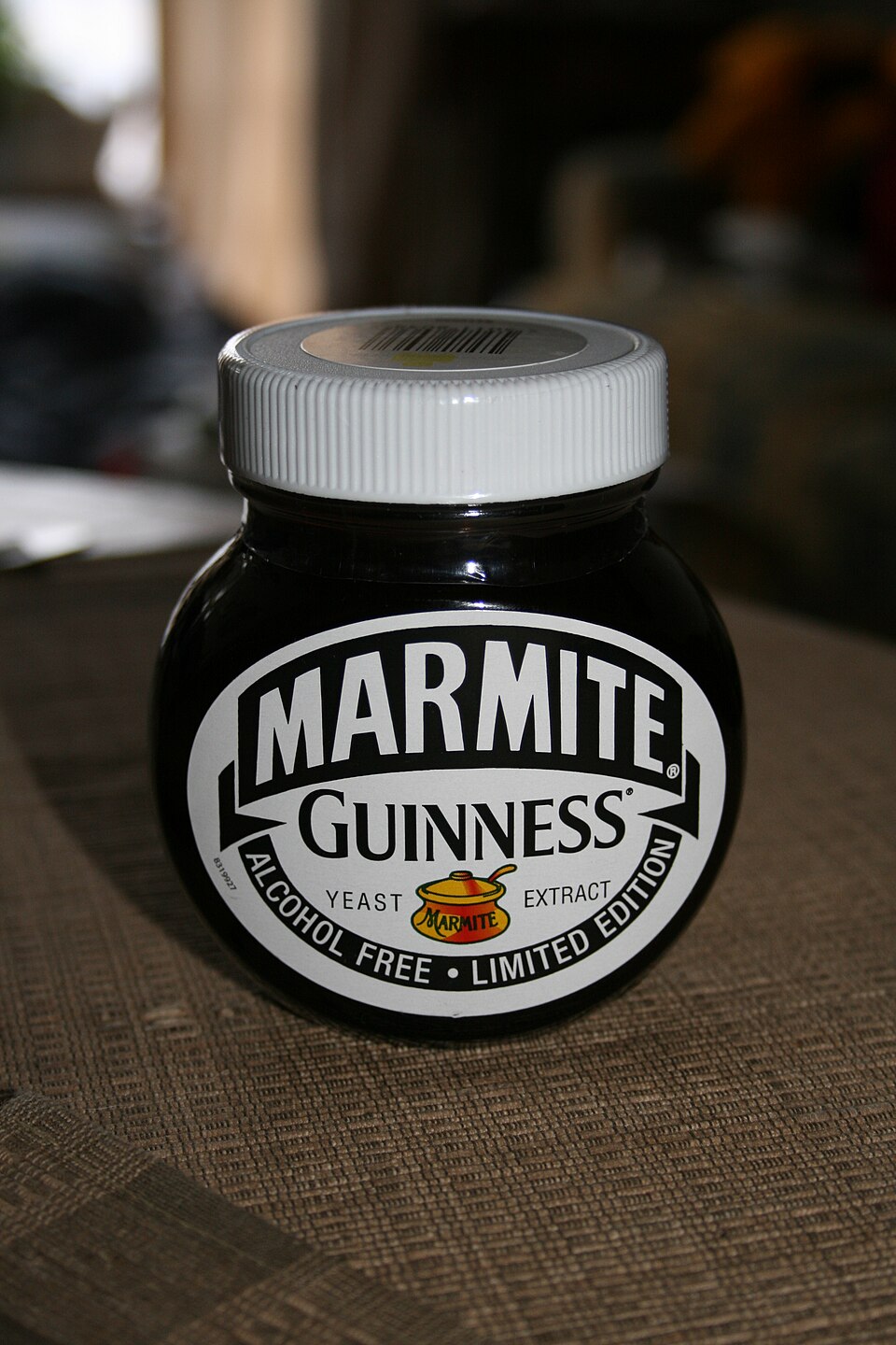 A squat dark Marmite jar with a white lid and a black-and-white label reading Marmite, Guinness, Alcohol Free and Limited Edition.