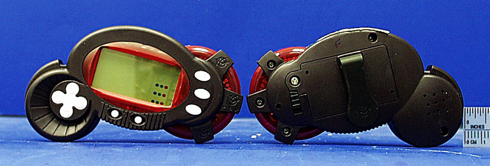 A red and black oval P-O-X unit is shown from the front and rear on a blue surface, with white buttons, a display, a belt clip and a small ruler.
