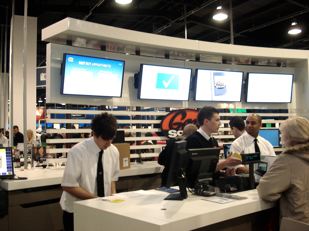 Service was part of Best Buy’s pitch to British customers. Lawton’s period photograph of its Geek Squad desk shows the advice-and-support setting promoted alongside the electrical goods, without establishing how well that promise worked.