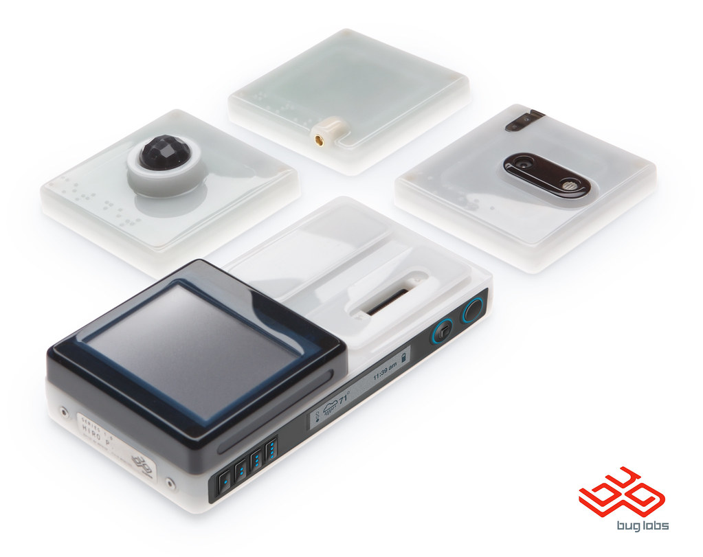 A translucent white BUGbase with an attached black touchscreen sits in front of three loose square modules, including a camera and domed sensor, on a white background with the Bug Labs logo.