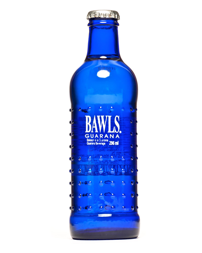 A capped cobalt-blue glass BAWLS Guarana bottle with raised bumps and white English/French296ml lettering stands against a white background.
