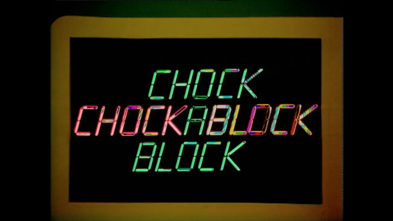 Black screen bordered by a thick yellow frame, displaying the words “CHOCK CHOCKABLOCK BLOCK” in green, red, and multicoloured segmented lettering.
