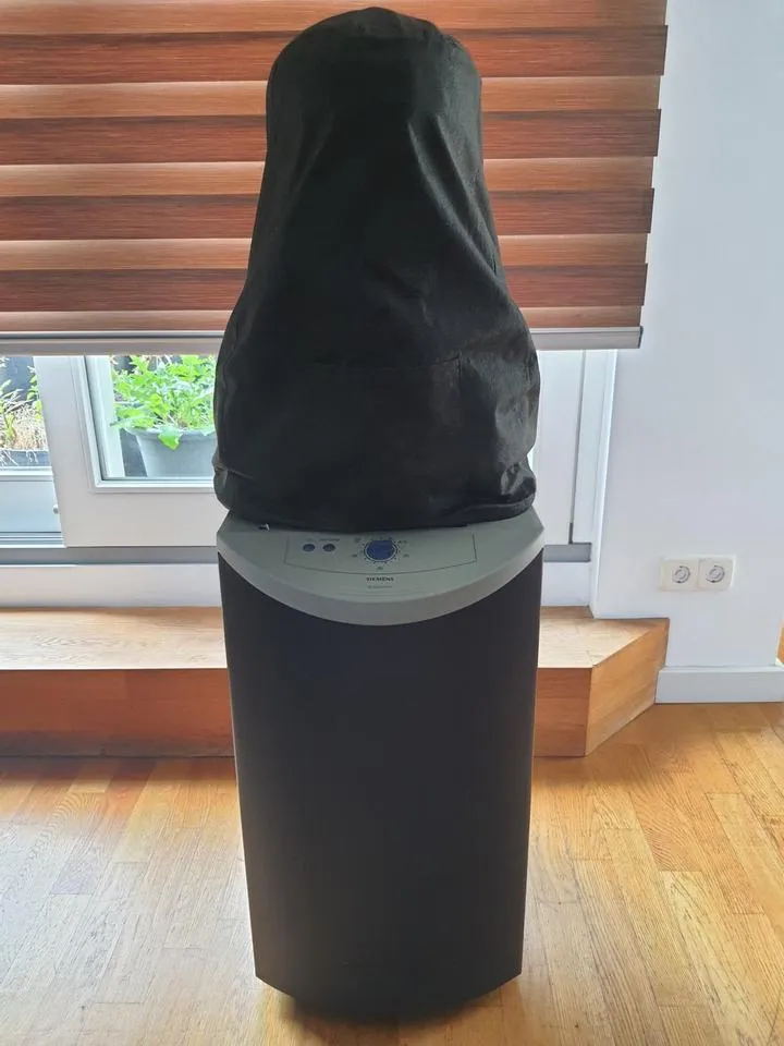 Siemens dressman with its torso lowered beneath a black fabric cover, showing the grey control panel and dark wheeled base.