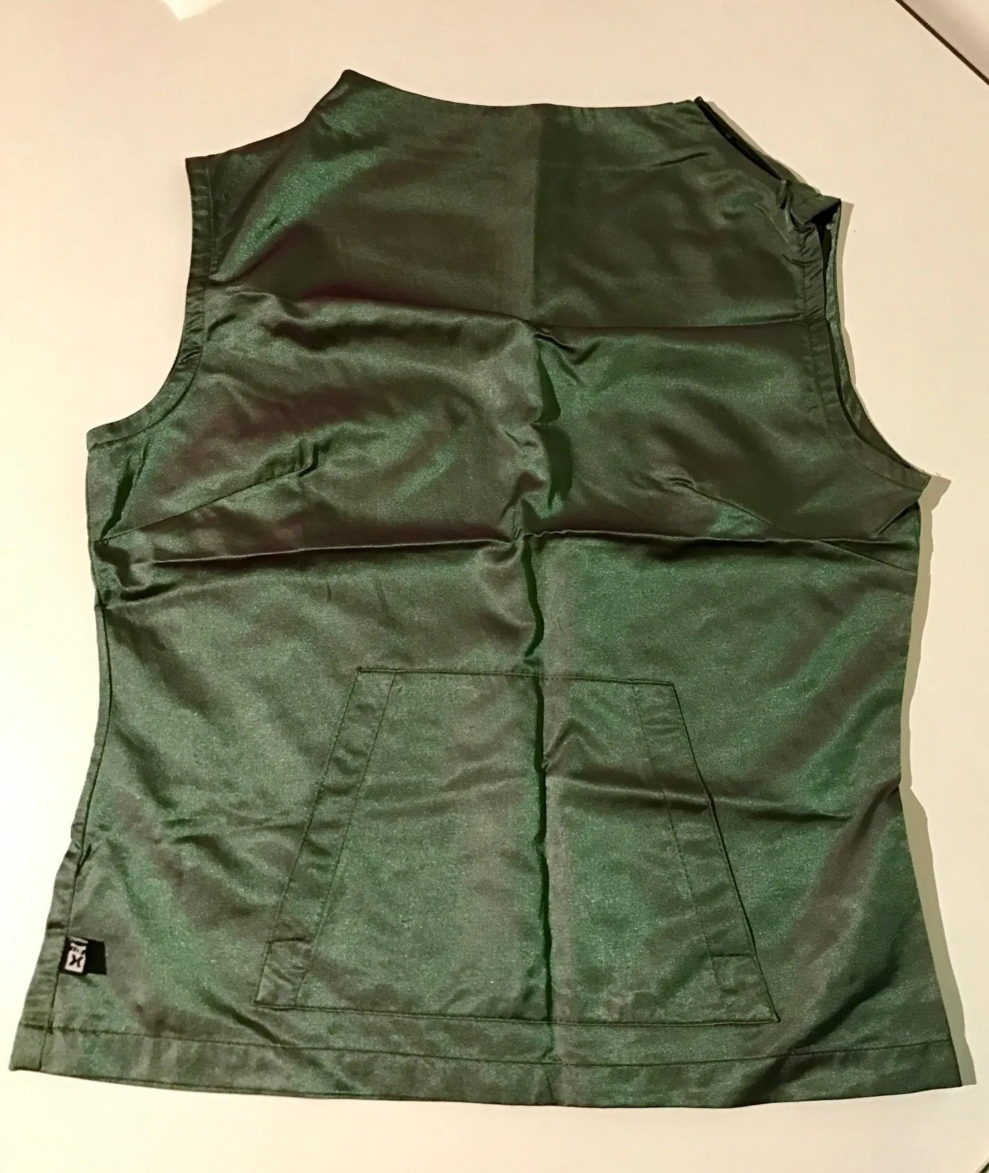 Emerald and grey sleeveless MY X vest laid flat, with a small MY X tag near the lower side seam.