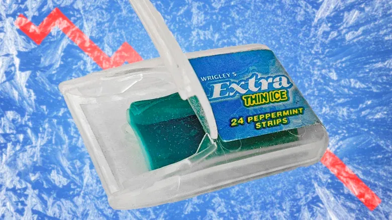 An open translucent plastic dispenser on a blue ice-textured background, containing a stack of turquoise rectangular strips. Its blue label reads “Wrigley’s Extra Thin Ice” and “24 Peppermint Strips.”