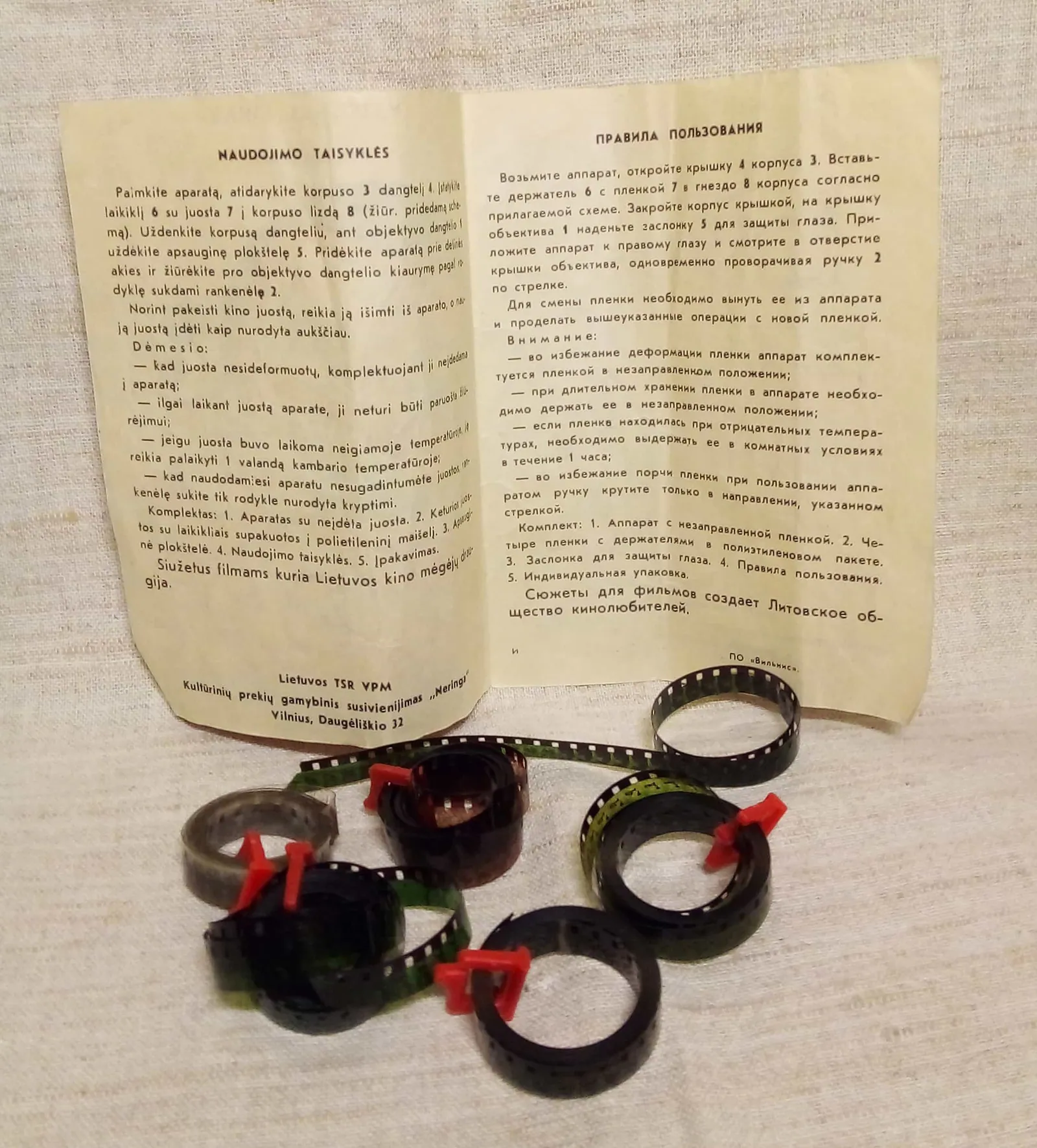 Open Lithuanian and Russian instruction leaflet displayed behind several looped films in plastic holders.
