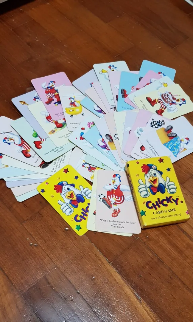 KFC Chicky Club playing cards spread across a wooden table beside a yellow box featuring the Chicky mascot.