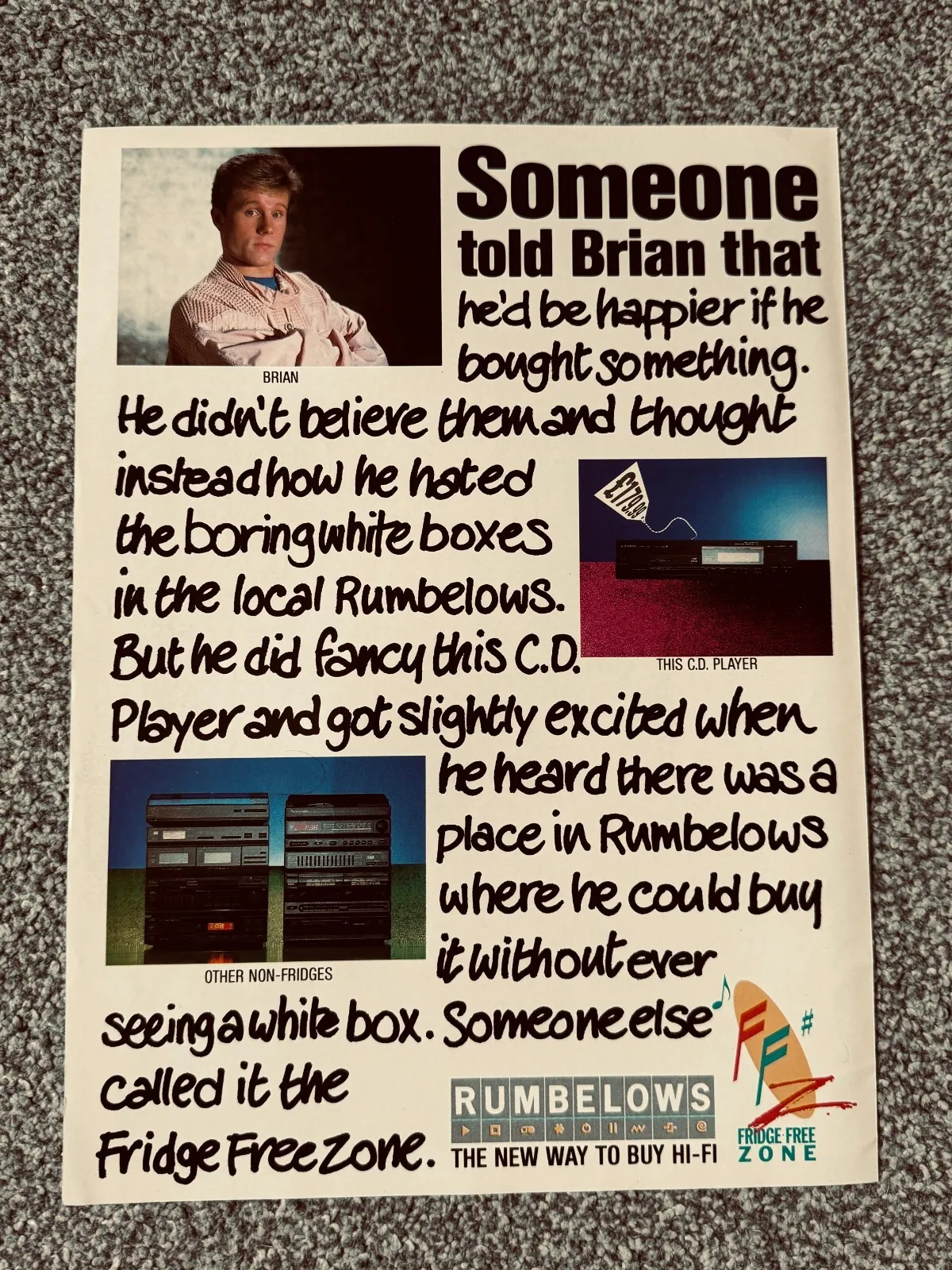 Photograph of a printed Rumbelows advertisement on grey patterned carpet. A man labelled “BRIAN” appears at upper left, with photographs of a CD player and stacked hi-fi units alongside text about buying hi-fi in the “Rumbelows Fridge Free Zone”.