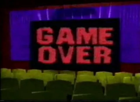 Red GAME OVER lettering on a studio screen above lime-green seats, surrounded by purple curtains.